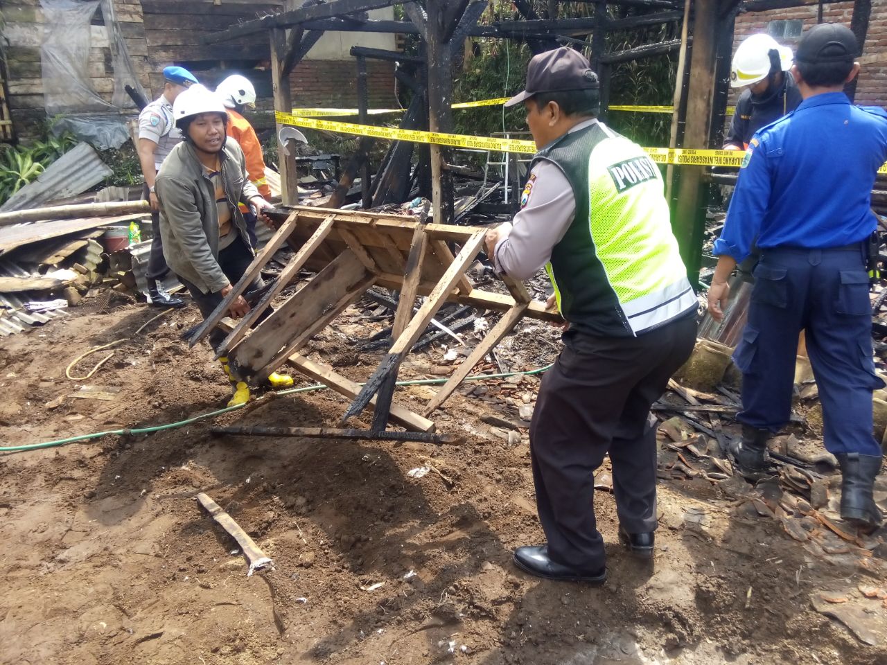 Anggota Polsek Bumiaji membantu korban kebakaran rumah di Ds. Tulungrejo