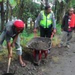 Anggota Bhabinkamtibmas Polsek Kasembon Polres Batu Bantu Warga Memperbaiki Jalan Yang Rusak